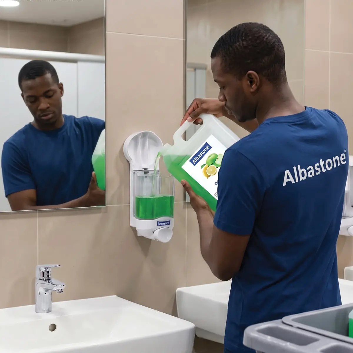 Agent ALBASTONE rechargeant un distributeur de savon dans des sanitaires collectifs à Mayotte